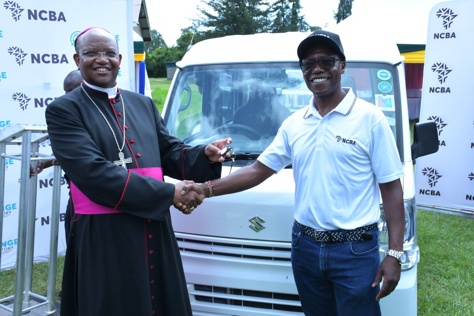 NCBA MD John Gachora presents vehicle keys to Archbishop Anthony Muheria
